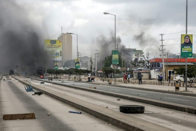 (Photo d'archives) Des manifestants se précipitent pour aider un blessé près de barricades en feu, pendant des affrontements à Dar es Salaam (Tanzanie) le 29 octobre 2025, pendant les élections présidentielle et législatives ( AFP / - )