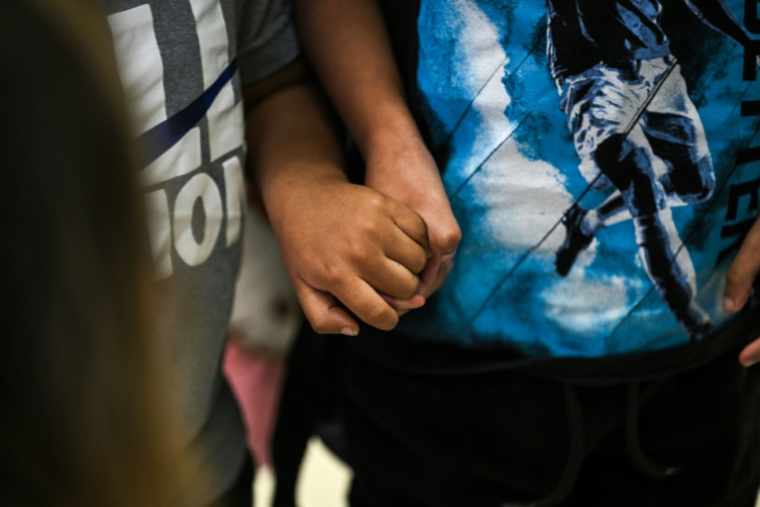 Deux enfants américains se tiennent le main à l'aéroport international de Miami avant de se rendre au Guatemala, le 4 décembre 2025  ( AFP / CHANDAN KHANNA )