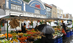 Des clients font leurs achats à un étal de fruits et légumes sur Portobello Road, à Londres