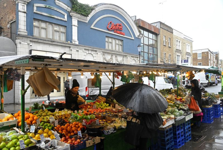 Des clients font leurs achats à un étal de fruits et légumes sur Portobello Road, à Londres