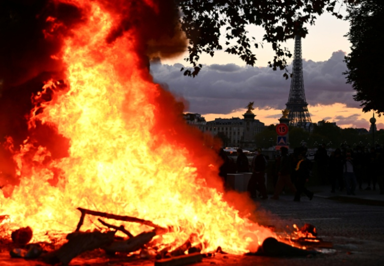 Un incendie à Paris le jour des manifestations "contre la vie chère", avec la tour Eiffel en arrière-plan, le 17 octobre 2026 ( AFP / Guillaume Saligot )