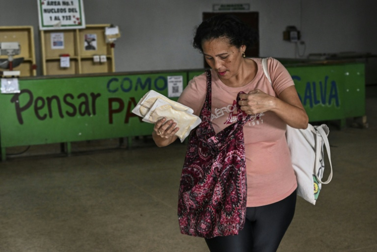 Une femme emporte un paquet de viande de poulet sous vide, faisant partie de l’aide humanitaire offerte par le Mexique aux familles cubaines dans un entrepôt de La Havane, le 6 mars 2026 ( AFP / YAMIL LAGE )