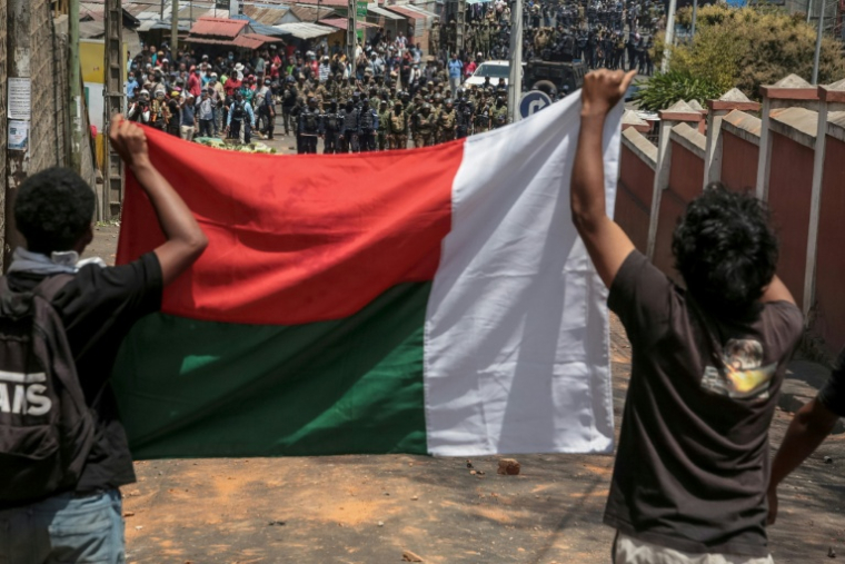 Des manifestants exhibent le drapeau malgache face aux forces de sécurité lors d'un mouvement de protestation contre les coupres d'eau et d'électricité à Antananarivo, le 25 septembre 2025.  ( AFP / RIJASOLO )