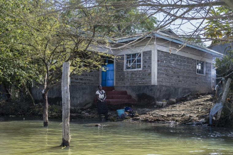 Faith Mpayei, 40 ans, se tient le 28 juillet 2026 à Marigat, au Kenya, devant sa maison, dont l'eau approche du perron après avoir quasiment submergé ce qui était une parcelle de deux hectares ( AFP / Tony KARUMBA )