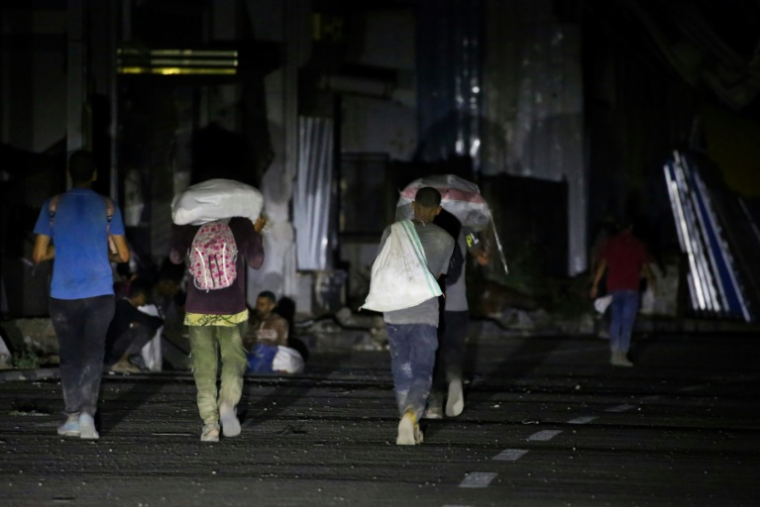 Des Palestiniens reviennent d'un point de distribution d'aide alimentaire mis en place par la Fondation humanitaire de Gaza (GHF) sur la route de Salaheddin, au camp de réfugiés de Nousseirat, dans le centre de la bande de Gaza, le 24 juin 2025 ( AFP / Eyad BABA )