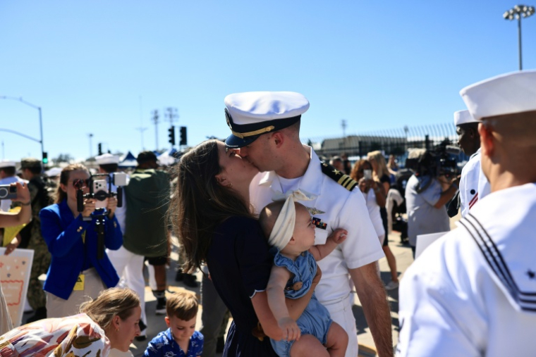 Des familles se réjouissent à l'arrivée du porte-avions américains USS Abraham Lincoln sur la base navale de San Diego, en Californie, le 8 octobre 2026 ( AFP / David Swanson )