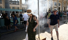 Des piétons se rafraîchissent sous un brumisateur installé par la mairie de Paris pendant une vague de chaleur à Paris, le 21 juin 2026 ( AFP / Guillaume BAPTISTE )