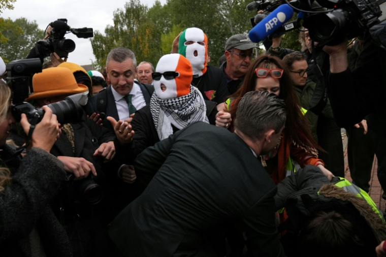 Les membres du groupe Kneecap, dont le chanteur Liam O'Hanna, alias Mo Chara, portent des cagoules aux couleurs du drapeau irlandais à leur arrivée au tribunal de Woolwich, à Londres, le 26 septembre 2025 ( AFP / CARLOS JASSO )