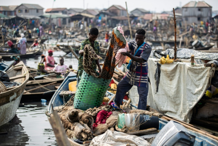 Des habitants transportent leurs affaires pendant la démolition de maisons du bidonville flottant de Makoko, le 9 janvier 2026 à Lagos, au Nigeria ( AFP / TOYIN ADEDOKUN )