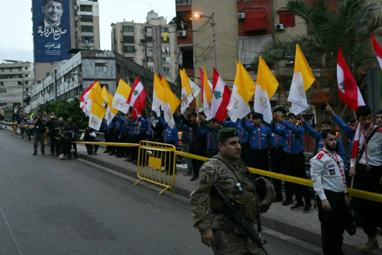 Des scouts tiennent des drapeaux libanais et du Vatican le long d'une route en attendant le passage du pape Léon XIV en visite de deux jours à Beyrouth, le 30 novembre 2025 au Liban ( AFP / Andreas SOLARO )