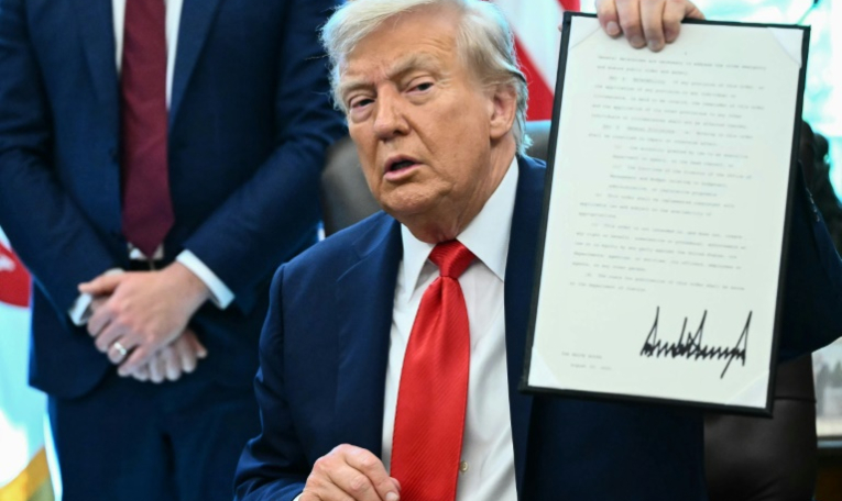 Le président américain Donald Trump montre un décret qu'il vient de signer dans le Bureau ovale à la Maison Blanche, le 25 août 2025 à Washington ( AFP / Mandel NGAN )