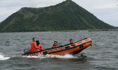 Des garde-côtes à bord d'un bateau pneumatique se dirigent vers le site où les corps personnes liées aux combats de coq sauraient été jetés dans le lac Taal, au sud de Manille, le 10 juillet 2025 aux Philippines ( AFP / Ted ALJIBE )