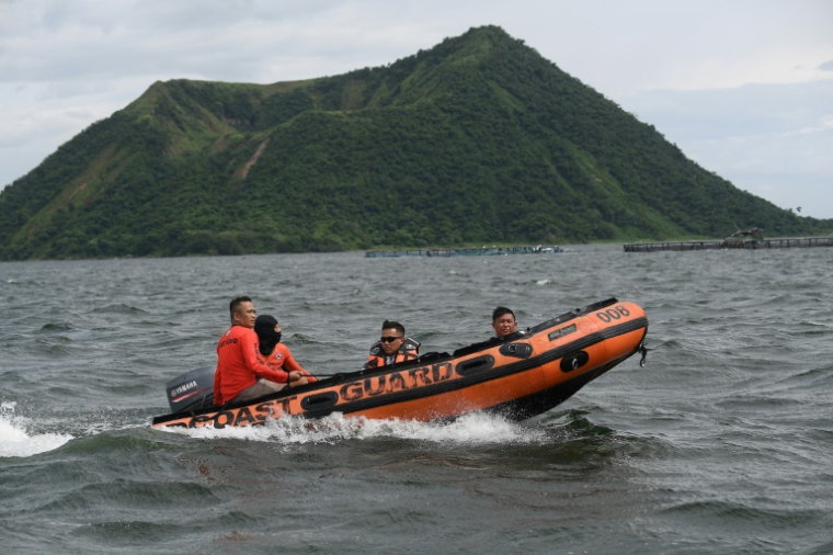 Des garde-côtes à bord d'un bateau pneumatique se dirigent vers le site où les corps personnes liées aux combats de coq sauraient été jetés dans le lac Taal, au sud de Manille, le 10 juillet 2025 aux Philippines ( AFP / Ted ALJIBE )