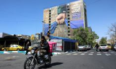 Un homme à moto passe devant un panneau faisant référence au détroit d'Ormuz, le 15 avril 2026 à Téhéran ( AFP / - )