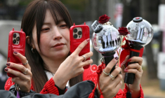 Des fans prennent des photos de bâtons lumineux à l'effigie de BTS à leur arrivée au stade où le groupe de K-pop se produira, à Goyang, le 9 avril 2026 ( AFP / Jung Yeon-je )