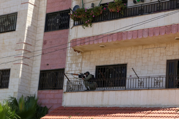Un membre des forces de sécurité syriennes prend position sur le balcon d'un immeuble à Soueida, le 15 juillet 2025 ( AFP / Bakr ALKASEM )
