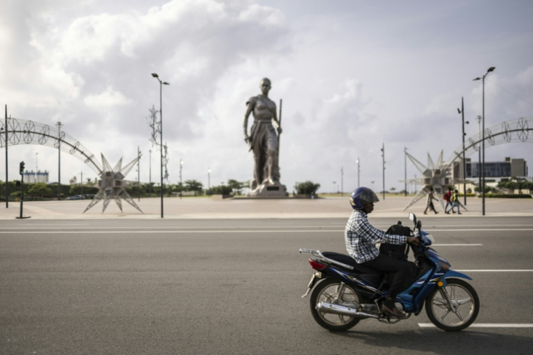Un motocycliste passe devant la statue de l'Amazone à Cotonou (Bénin), le 8 décembre 2025 ( AFP / OLYMPIA DE MAISMONT )
