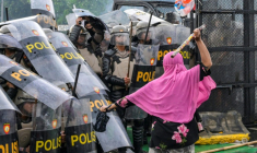 Une femme frappe le bouclier d'un policier avec un bâton de bambou alors que la police repousse les étudiants lors d'une manifestation devant le Parlement contre une hausse des allocations pour les députés, à Jakarta le 28 août 2025 ( AFP / BAY ISMOYO )