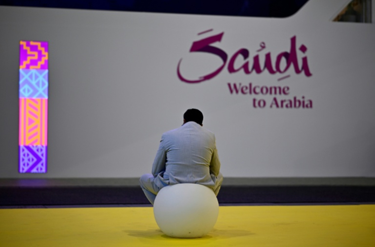Un visiteur assis devant le stand de l'Arabie saoudite à l'ouverture du salon du tourisme ITB à Berlin, le 3 mars 2026 ( AFP / Tobias SCHWARZ )