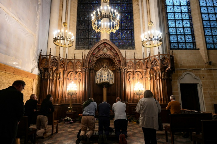 Des personnes prient à la chapelle Notre-Dame du Pilier et sa statue en noyer polychrome de la Vierge Marie perchée sur un pilier doré dans la cathédrale Notre-Dame de Chartres, le 5 juin 2025 en Eure-et-Loire ( AFP / JEAN-FRANCOIS MONIER )