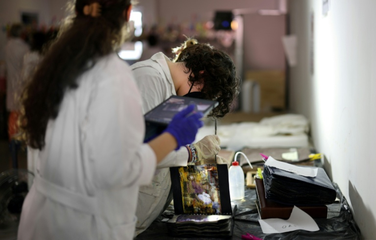 Des étudiants de l'Université des Beaux-Arts nettoient et restaurent des photos de famille par la boue pendant les inondations, le 2 octobre 2025 à Valence, en Espagne ( AFP / Thomas COEX )