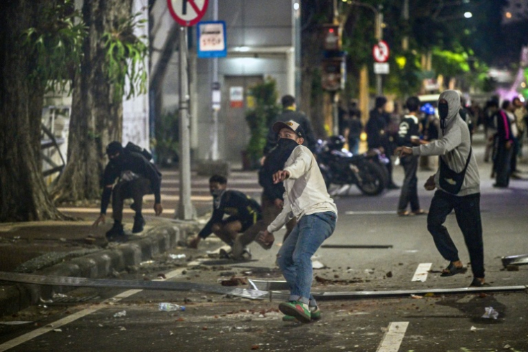 Des manifestants lancent des pierres contre les policiers lors d'un rassemblement contre la hausse du prix des carburants non subventionné et le programme phare de repas gratuits du président Prabowo, le 26 juin 2026 à Surabaya, en Indonésie ( AFP / Juni KRISWANTO )