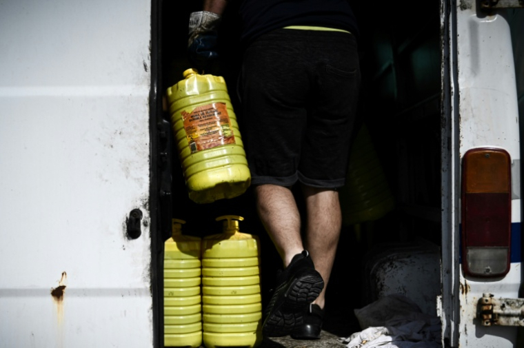 Un membre de "Roule ma frite", une association spécialisée dans la récupération et le recyclage des huiles de friture usagées en circuit court, lors d'une opération de collecte au Château-d'Oléron, sur l'île d'Oléron, le 10 mai 2022 ( AFP / Philippe LOPEZ )