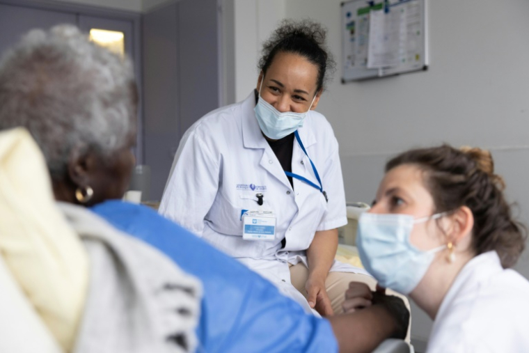 Une infirmière (à gauche) et une psychomotricienne (à droite) du service mobile de soins palliatifs au chevet d'une patiente à l'hôpital Antoine-Béclère de l'AP-HP, à Clamart, près de Paris, le 27 mai 2025 ( AFP / Thomas SAMSON )