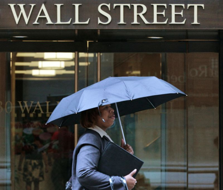 Une femme marche sous la pluie sur Wall Street à New York