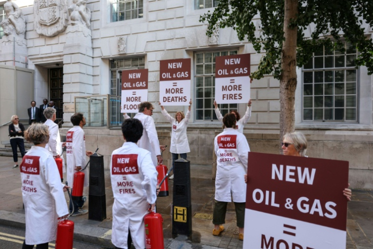 Des militants écologistes manifestent devant le bâtiment du ministère de la Sécurité énergétique et de la Neutralité carbone pour protester contre les forages pétroliers et gaziers, le 17 août 2026, à Londres ( AFP / Adrian DENNIS )
