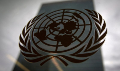 Le siège des Nations unies vu à travers une fenêtre avec le logo des Nations unies au premier plan