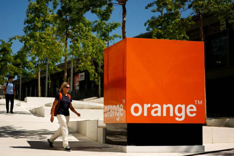 Une femme passe devant le logo d'Orange au siège de la société à Issy-les-Moulineaux