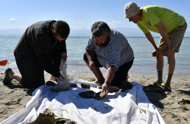 Maxime Menchikov et ses collègues examinent les objets découverts par des plongeurs au fond du lac Issyk-Koul, le 22 septembre 2026, près de  Torou-Aïguyr, au Kirghizstan ( AFP / Vyacheslav OSELEDKO )