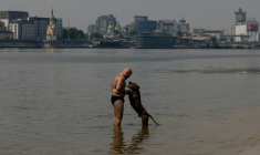 Un homme en maillot de bain joue avec son chien dans l'eau du fleuve Dniepr, à Kiev, en Ukraine, le 29 juin 2026. ( AFP / Tetiana DZHAFAROVA )
