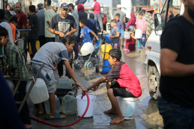 Des Palestiniens remplissent des seaux d'eau à un point de distribution dans le camp de réfugiés de Nousseirat, dans le centre de la bande de Gaza, le 10 juillet 2025 ( AFP / Eyad BABA )