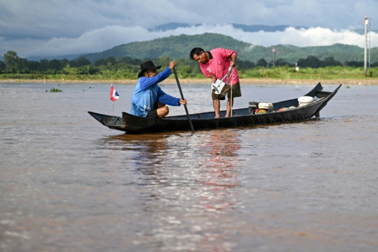 Le pêcheur Chaweng Yothaud (d) prélève des échantillons pour tester un empoisonnement à l'arsenic le long de la rivière Kok dans la région du Triangle d'or, dans la province de Chiang Rai, dans le nord de la Thaïlande, le 25 mai 2025 ( AFP / Manan VATSYAYANA )