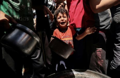 Un enfant pleure au milieu de Palestiniens qui attendent de recevoir un repas chaud distribué par une association caritative locale à Nousseirat, dans le centre de la bande de Gaza, le 24 mai 2025 ( AFP / Eyad BABA )