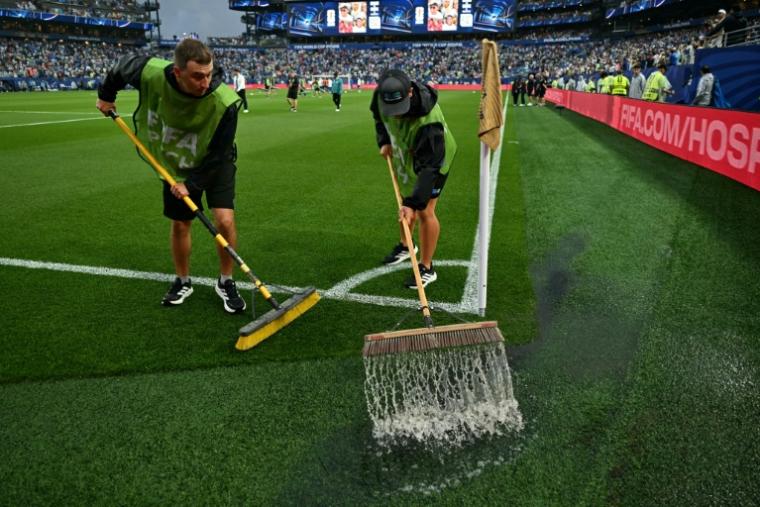 Des membres de l'entretien des terrains tentent d'évacuer l'eau de la pelouse du stade de Philadelphie durant une longue interruption du match France-Irak en phase de poules du Mondial, le 22 juin 2026 ( AFP / MAURO PIMENTEL )