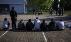 Des migrants sont assis par terre après avoir été arrêtés par la police allemande