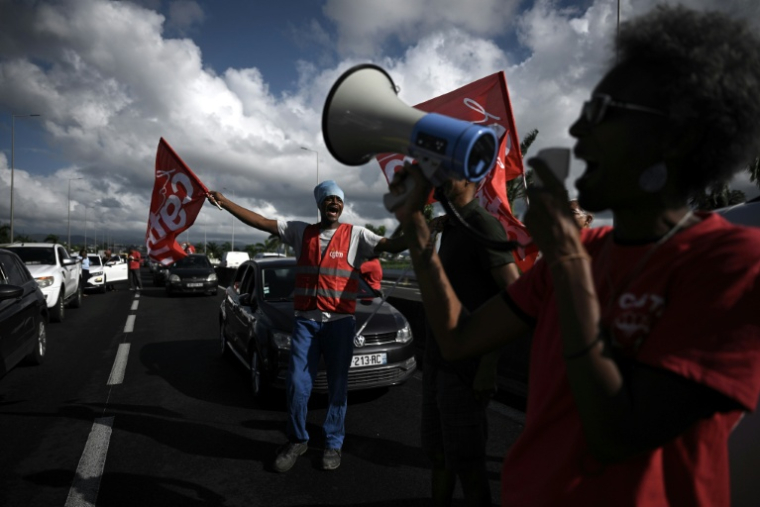 Des membres de la CGT Martinique manifestent le 15 octobre 2024 sur la route menant à l'aéroport de Fort-de-France, en plein mouvement contre la vie chère ( AFP / Philippe LOPEZ )