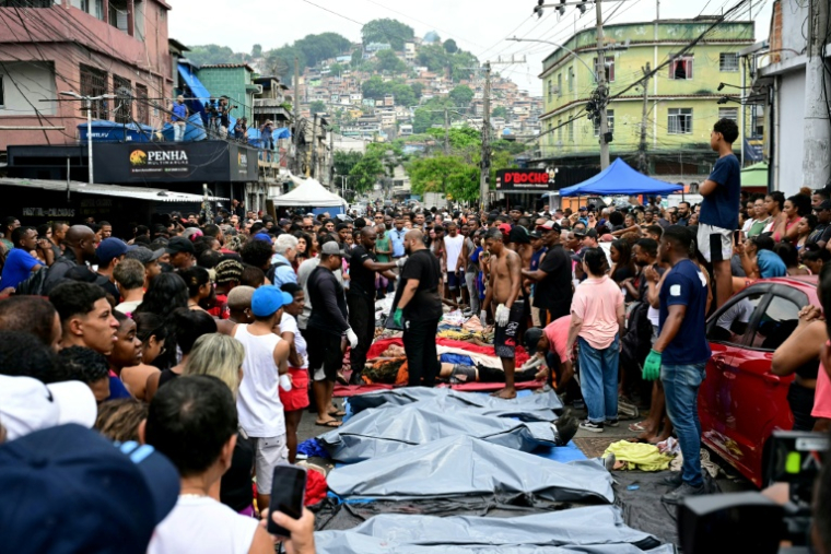 Des habitants se tiennent devant des corps alignés  dans une des favelas du Complexo da Penha, à Rio de Janeiro, le 29 octobre 2025 ( AFP / Pablo PORCIUNCULA )