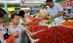 Des clients choisissent des tomates sur un étal à l'intérieur d'un marché du matin à Pékin, en Chine