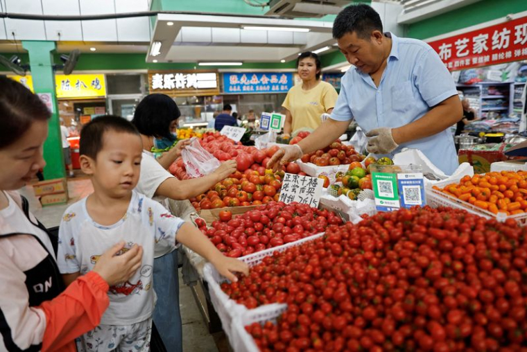 Des clients choisissent des tomates sur un étal à l'intérieur d'un marché du matin à Pékin, en Chine