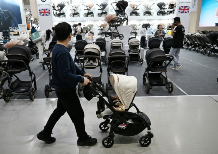 Un homme avec sa poussette dans une allée d'un salon de l'enfant, le 30 avril 2026 à Séoul  ( AFP / Jung Yeon-je )