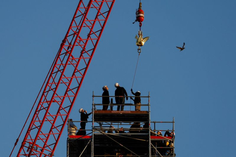 Photo d'une grue qui a hissé un nouveau coq en cuivre au sommet de la flèche flambant neuve de la cathédrale Notre-Dame de Paris