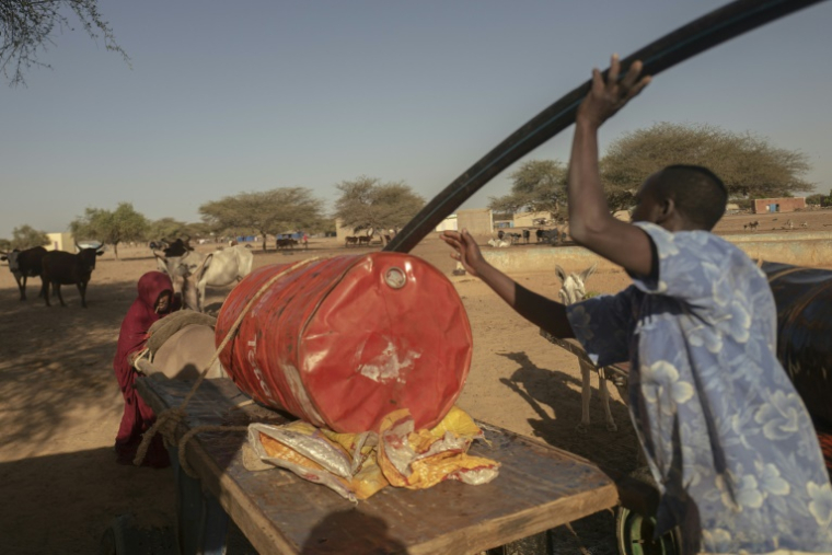 Un réfugié malien, qui a fui avec sa famille la ville de Leré, remplit un baril utilisé comme réservoir d'eau alors qu'il traverse la frontière mauritanienne au poste frontière de Douankara à Fassale, le 4 novembre 2025. ( AFP / MICHELE CATTANI )