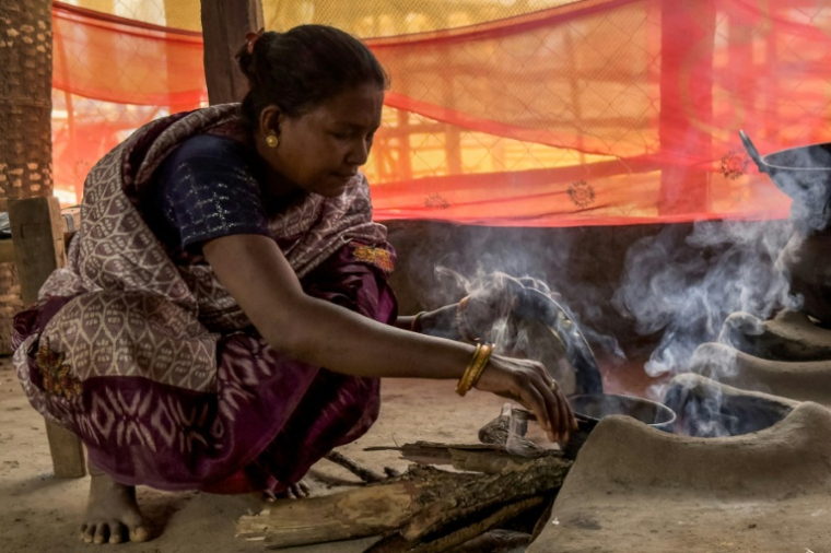 Somari Negi, veuve de Rameshwar Negi, tué l'année dernière par les paramilitaires qui le soupçonnaient d'être un rebelle maoïste, prépare un repas chez elle à Marda, dans le district de Bastar de l'Etat de Chhattisgarh, le 14 mars 2025 dans le centre de l'Inde ( AFP / Jalees ANDRABI )