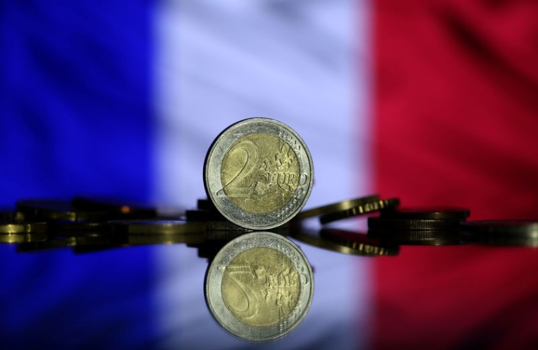 Des pièces en euros sont visibles devant le drapeau français sur cette photo.
