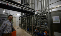 Un employé pose à côté d'une unité de désalcoolisation du vin dans le laboratoire du Chai sobre, le 25 juin 2025 à à Vic-Fezensac, dans le Gers  ( AFP / Lionel BONAVENTURE )