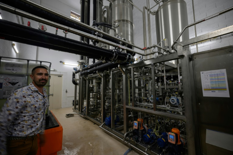 Un employé pose à côté d'une unité de désalcoolisation du vin dans le laboratoire du Chai sobre, le 25 juin 2025 à à Vic-Fezensac, dans le Gers  ( AFP / Lionel BONAVENTURE )